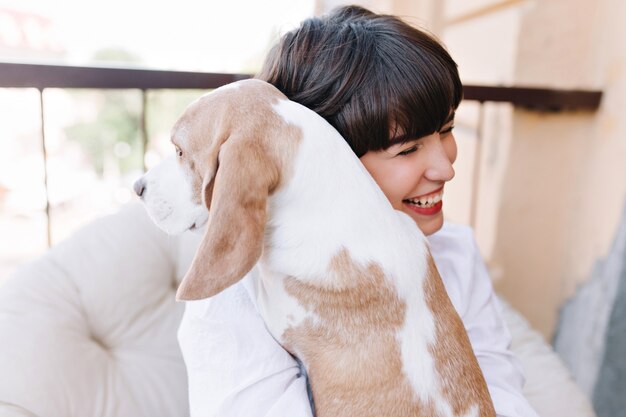 Portrait d'une fille incroyable en riant, tout en embrassant le chien beagle à la voiture