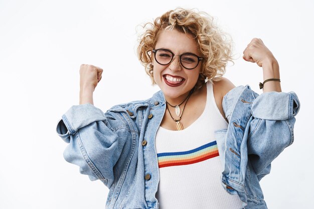 Portrait d'une fille insouciante joyeuse et joyeuse amusée et excitée avec des cheveux courts et juste levant les poings serrés dans le triomphe et la célébration le nez plissé et souriant de joie