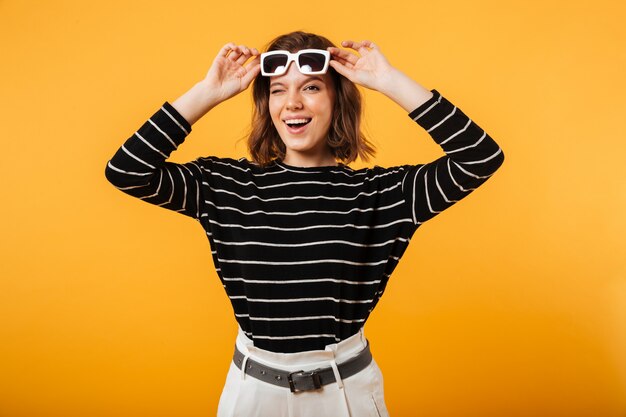 Portrait d'une fille joyeuse en lunettes de soleil un clin de œil