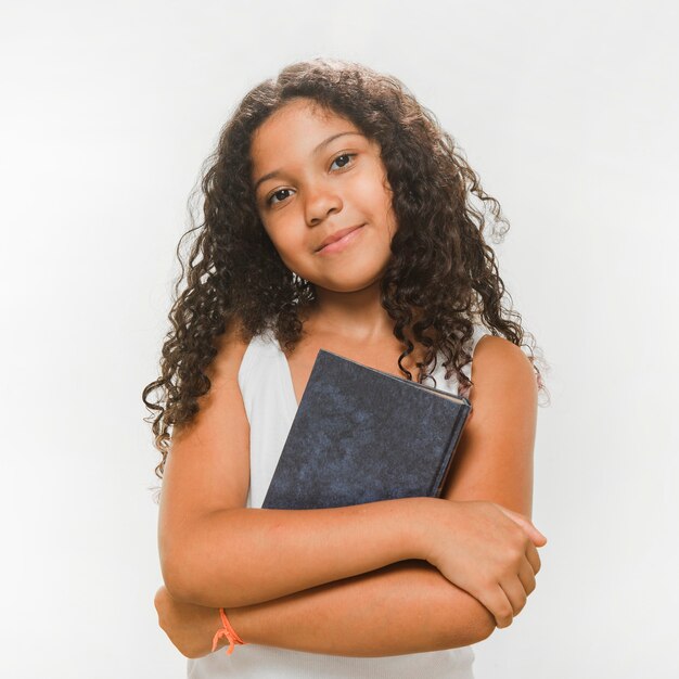 Portrait d&#39;une fille avec un livre en pliant ses bras