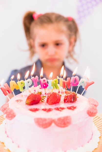 Portrait flou d&#39;une fille triste debout derrière le gâteau d&#39;anniversaire aux fraises