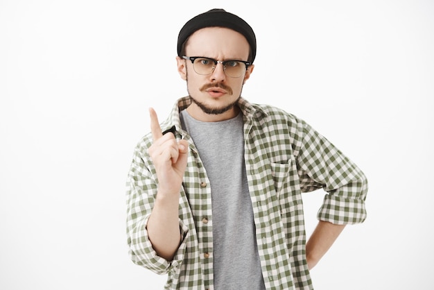 Portrait de frère sérieux et autoritaire strict avec barbe et lunettes portant bonnet noir hipster secouant l'index