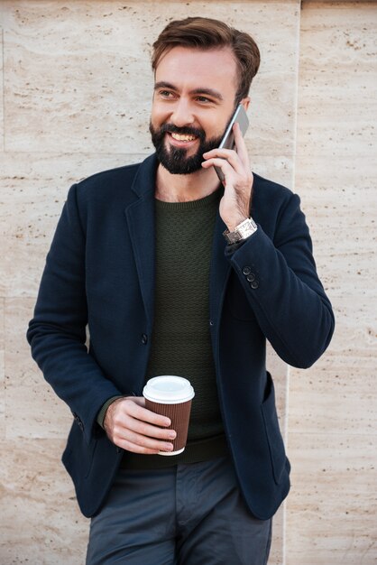 Portrait d'un gai homme barbu tenant une tasse de café