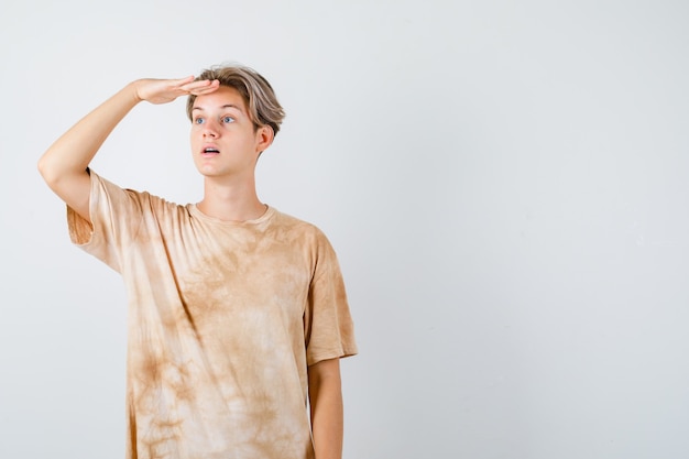 Portrait d'un garçon adolescent regardant au loin avec la main sur la tête en t-shirt et se demandait la vue de face