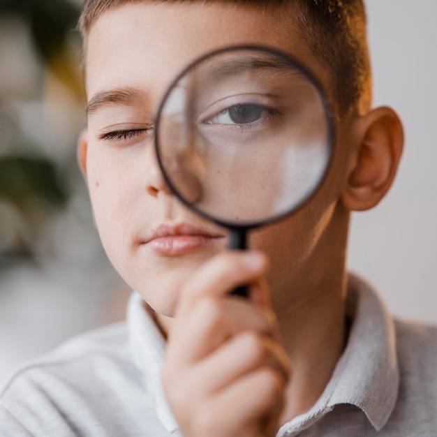 Portrait de garçon à l'aide d'une loupe en classe