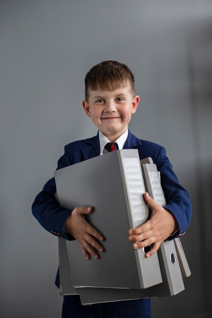 Portrait d'un garçon mignon portant un costume et tenant des fichiers de bureau