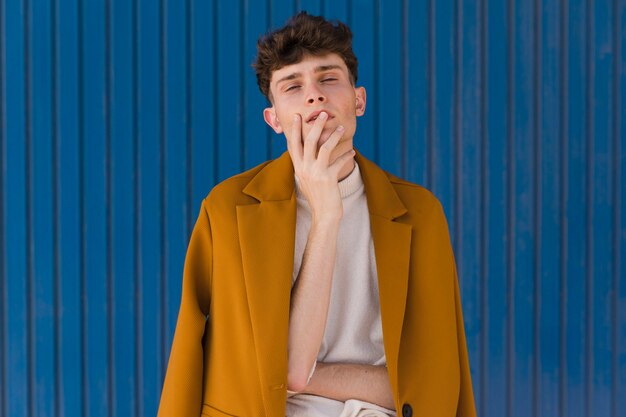 Portrait d'un garçon à la mode contre le mur bleu