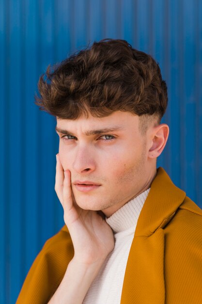 Portrait d'un garçon à la mode contre le mur bleu