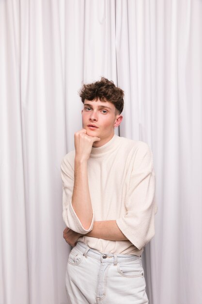Portrait d&#39;un garçon à la mode devant un rideau blanc