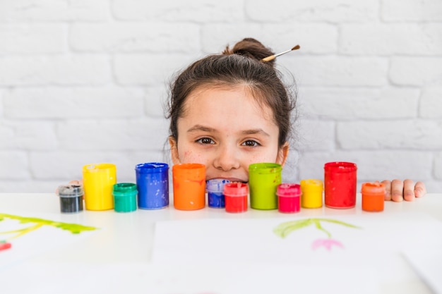 Portrait, girl, regarder, coloré, peinture, bouteilles, bord, blanc, table