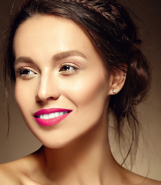 Portrait glamour de belle femme modèle femme avec un maquillage quotidien frais avec des lèvres rouges et un visage propre et une coiffure ondulée romantique sur un mur marron