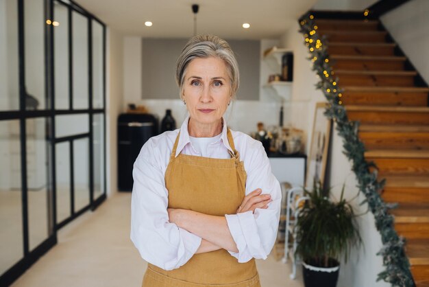 Portrait de grand-mère stricte debout dans une pose mécontente regardant fixement la caméra en colère