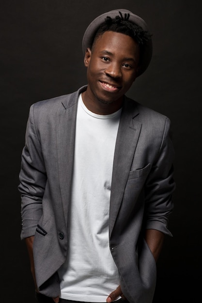 Photo gratuite portrait en gros plan d'un bel homme noir avec un sourire charmant. prise de vue en studio d'un africain bien habillé portant un chapeau et une veste.