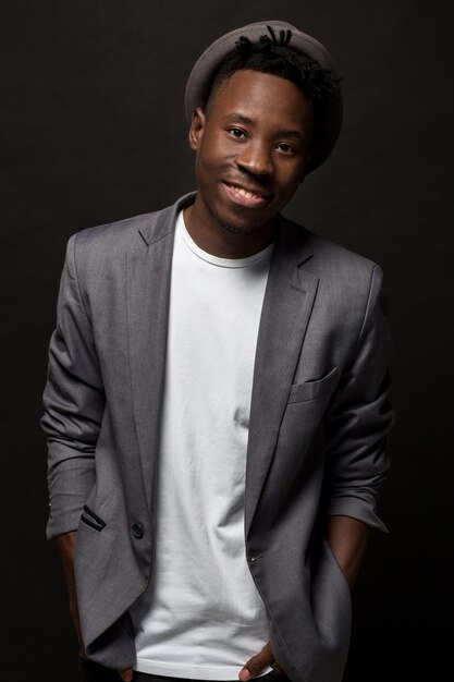 Portrait en gros plan d'un bel homme noir avec un sourire charmant. Prise de vue en studio d'un Africain bien habillé portant un chapeau et une veste.