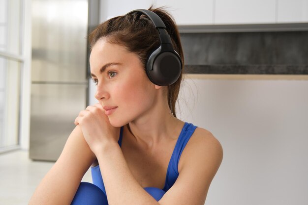 Portrait en gros plan d'une belle femme brune portant des écouteurs écoutant de la musique et faisant de l'exercice