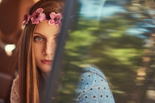 Portrait en gros plan d'une belle femme vêtue d'une robe blanche et d'une couronne blanche sur la tête, assise dans la voiture sur le siège arrière.