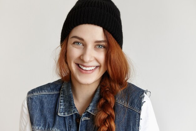 Portrait de gros plan de la belle jeune femme européenne rousse avec tresse souriant joyeusement