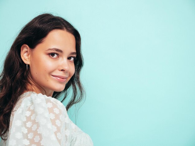 Portrait en gros plan d'une belle jeune femme souriante en robe d'été à la mode Sexy femme insouciante posant près d'un mur bleu en studio Modèle positif s'amusant à l'intérieur Enthousiaste et heureux