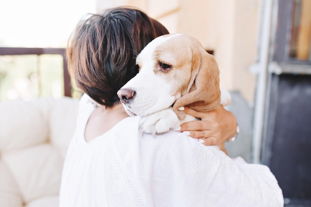 Portrait de gros plan de chien beagle triste à la recherche de suite par-dessus l'épaule de fille brune