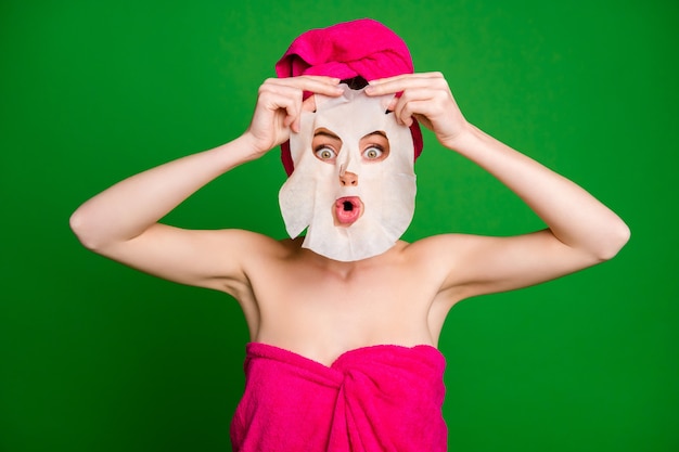 Portrait en gros plan d'une dame géniale se demandant portant un turban utilisant un masque facial comme des lèvres fantasmagoriques de moue fantôme isolées sur un fond de couleur vert vif