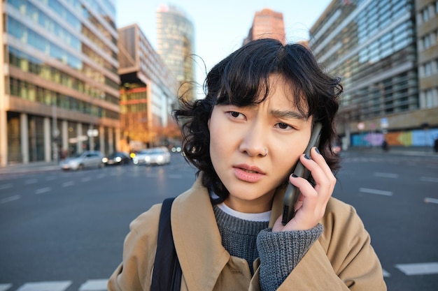 Portrait en gros plan d'une femme asiatique concernée parle sur un téléphone mobile et entend de mauvaises nouvelles semble inquiète fe