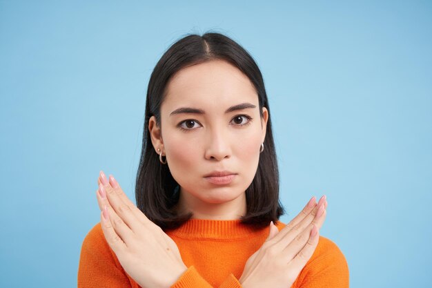Portrait en gros plan d'une femme asiatique sérieuse montre un signe d'arrêt désapprouve quelque chose refuse ou rejette s