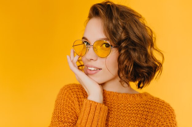 Portrait en gros plan d'une femme blanche sensuelle aux cheveux bouclés touchant son visage avec la main