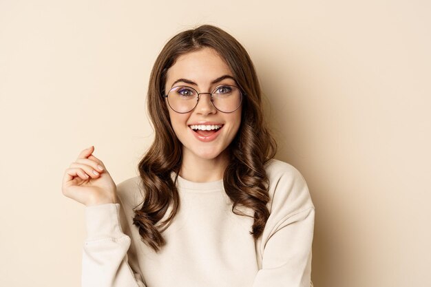 Portrait en gros plan d'une femme brune élégante à lunettes riant et souriant posant dans des lunettes contre...