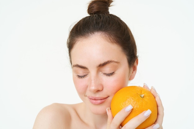 Photo gratuite portrait en gros plan d'une femme brune tenant un visage orange près d'un fond blanc