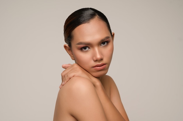 Portrait en gros plan d'une femme joyeuse embrassant ses sentiments avec des sourires charmants posant isolé sur un mur gris en studio, regardant la caméra