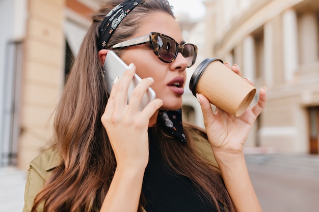 Portrait de gros plan de femme latine occupée, parler au téléphone et tenant une tasse de thé