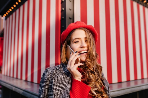 Portrait en gros plan d'une femme magnifique aux cheveux brillants, parler au téléphone sur fond rayé