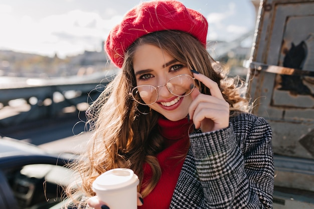 Portrait en gros plan d'une femme sensuelle aux cheveux bruns avec une tasse de boisson chaude posant dans une journée froide