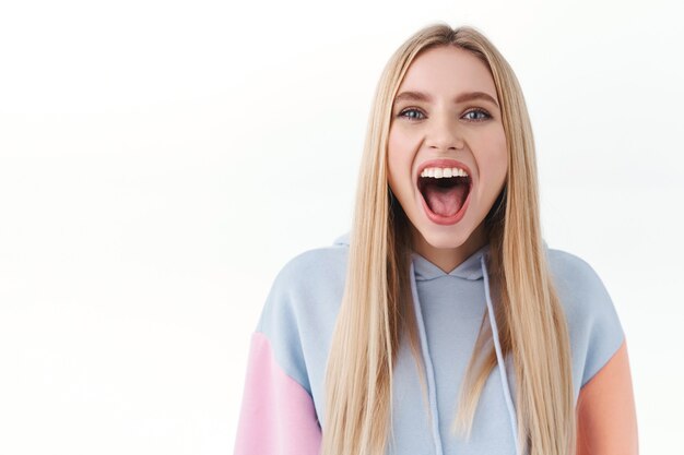 Portrait en gros plan d'une fille blonde enthousiaste et excitée qui assiste enfin au concert de sa chanteuse préférée