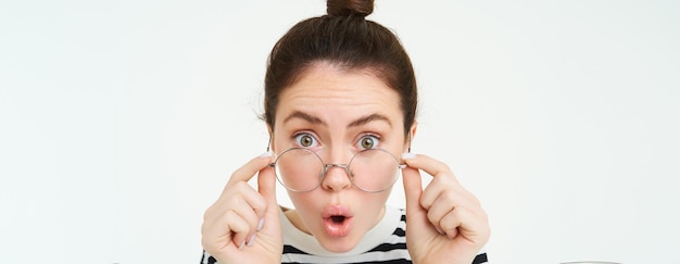 Portrait en gros plan d'une fille surprise qui enlève ses lunettes lit des nouvelles étonnantes impressionnée par quelque chose