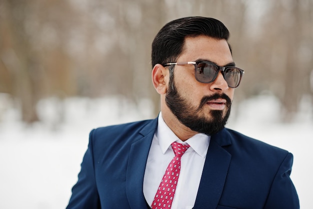 Portrait en gros plan d'un homme d'affaires indien élégant en costume et lunettes de soleil posé à la journée d'hiver en plein air