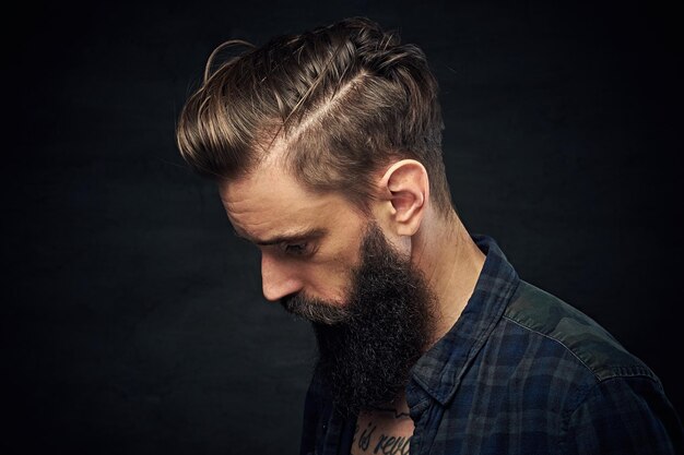 Portrait en gros plan d'un homme barbu aux cheveux longs sur fond sombre.