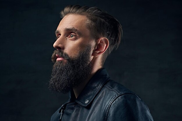 Portrait en gros plan d'un homme barbu portant une veste en cuir noire.