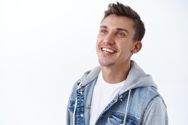 Portrait en gros plan d'un homme blond souriant rêveur et heureux regardant le coin supérieur gauche avec un sourire heureux