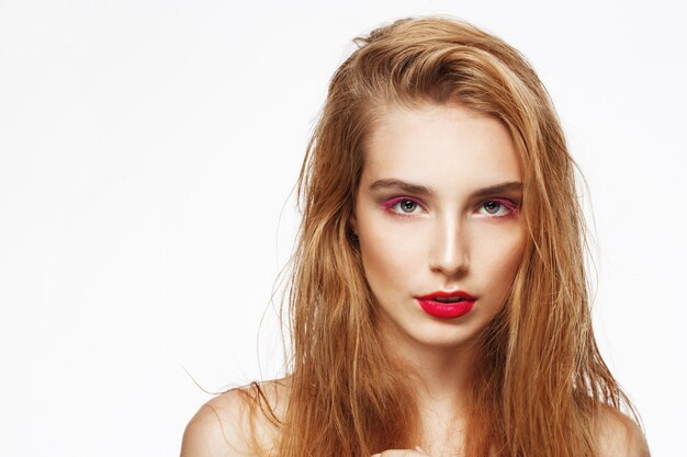 Portrait de gros plan de jeune belle fille réfléchie confiante avec maquillage lumineux. mur blanc. Isolé.