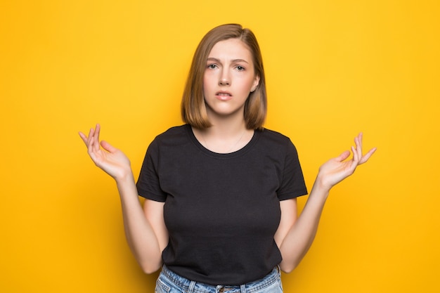 Portrait de gros plan de jeune femme assez surprise avec la bouche ouverte debout avec les paumes ouvertes