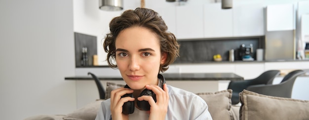Photo gratuite portrait en gros plan d'une jeune femme aux cheveux courts qui enlève ses écouteurs et termine d'écouter un livre électronique