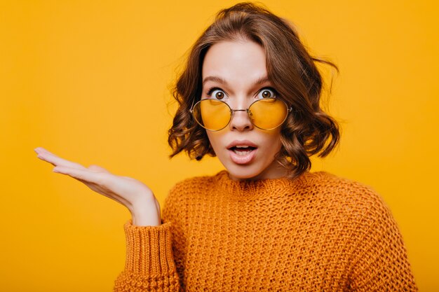 Portrait en gros plan d'une jeune femme choquée avec de grands yeux bruns et la bouche ouverte