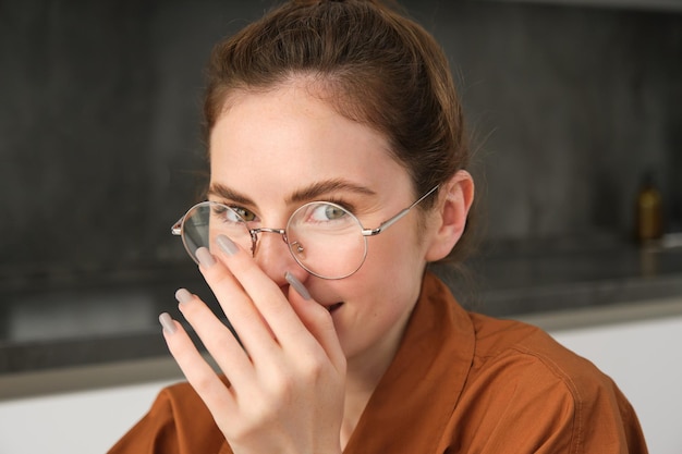 Photo gratuite portrait en gros plan d'une jeune femme mignonne avec des lunettes couvre son sourire en riant et en souriant