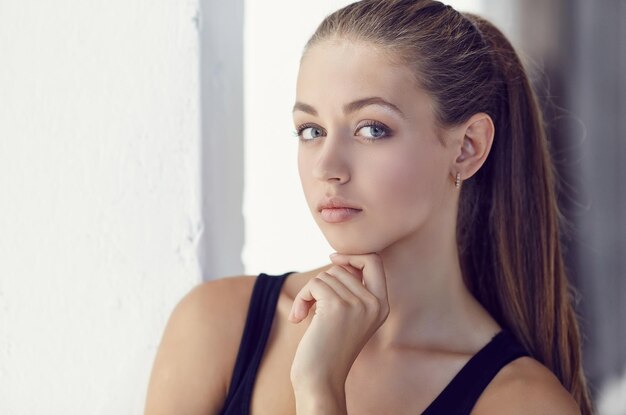 Portrait en gros plan d'une jeune femme mince aux longs cheveux bruns.