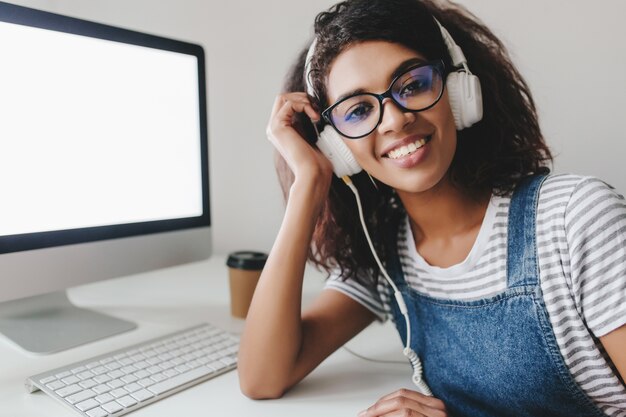 Portrait En Gros Plan D'une Jeune Femme Ravie Dans Des écouteurs Blancs Posant Pendant Le Processus De Travail Au Bureau