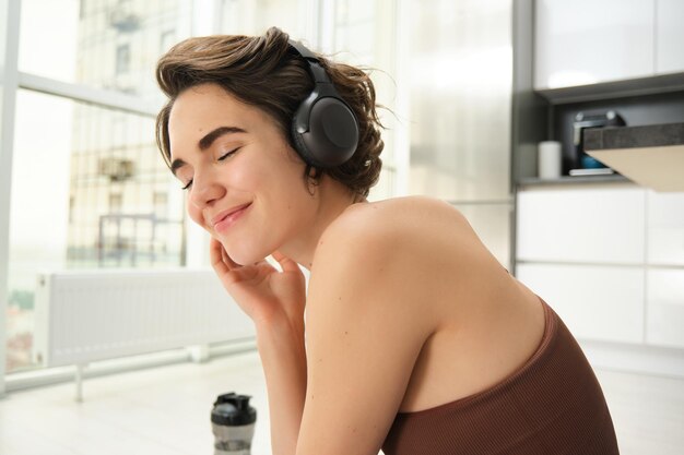 Portrait en gros plan d'une jeune femme souriante fitness girl in headphones écoute de la musique et fait de l'exercice t