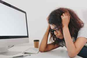 Photo gratuite portrait de gros plan de jeune femme triste se trouve près de l'ordinateur avec écran blanc et tasse de café