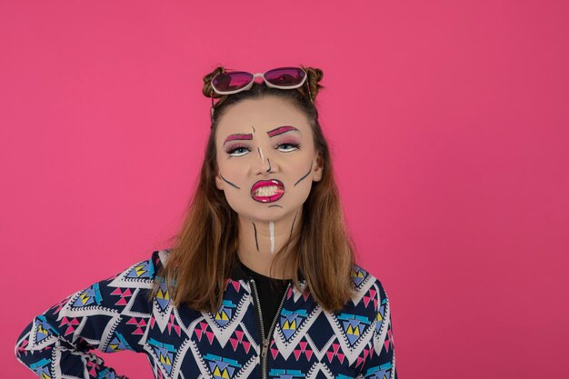 Portrait en gros plan d'une jeune fille portant un maquillage créatif et un chewing-gum sur fond rose. Photo de haute qualité