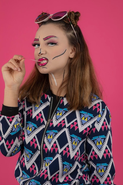 Portrait en gros plan d'une jeune fille portant un maquillage créatif et étirant sa gomme tout en regardant la caméra. Photo de haute qualité